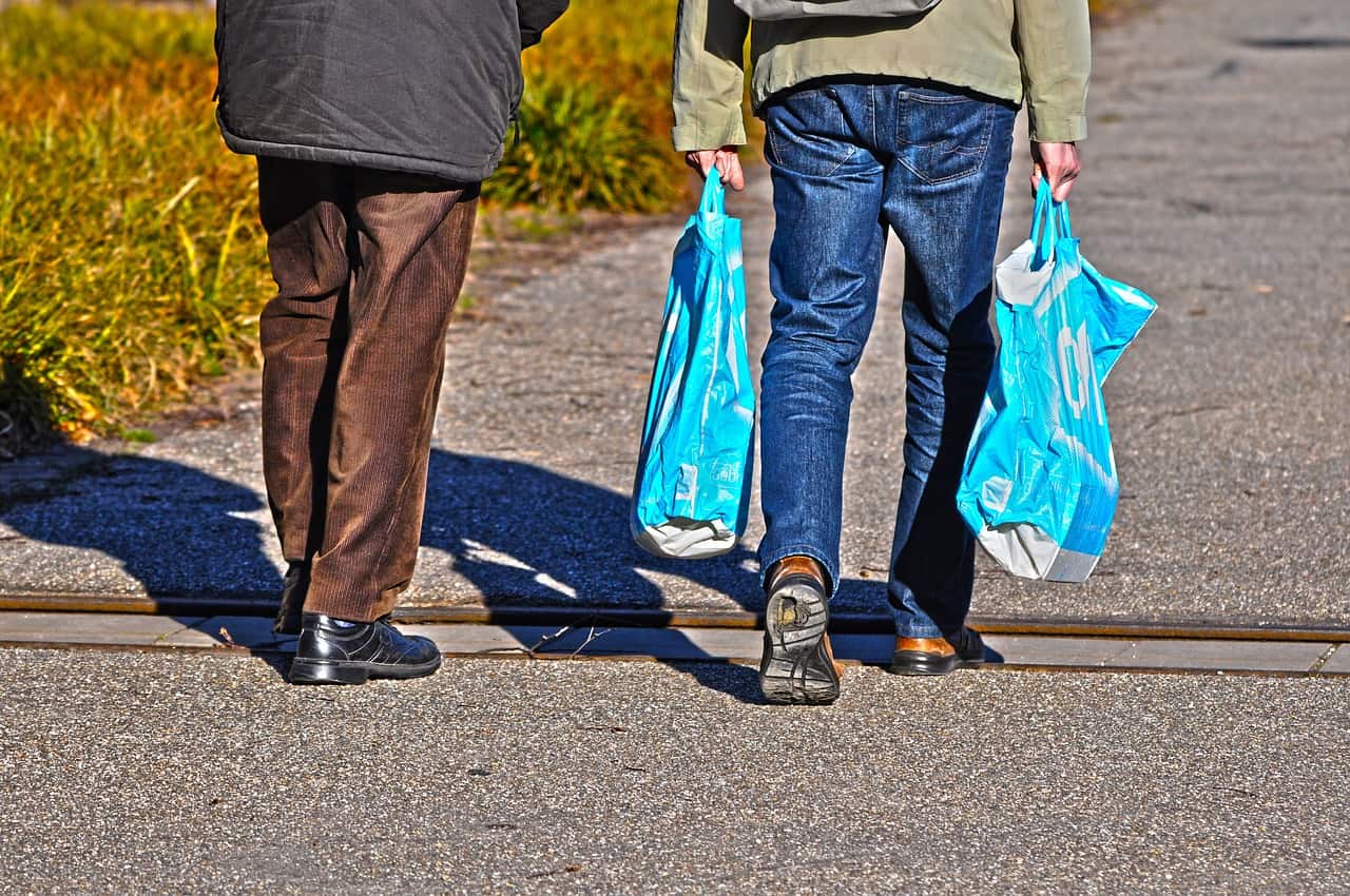 Men walking with plastic carrier bags.