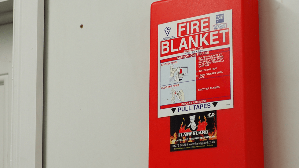 Fire blanket attached to a wall