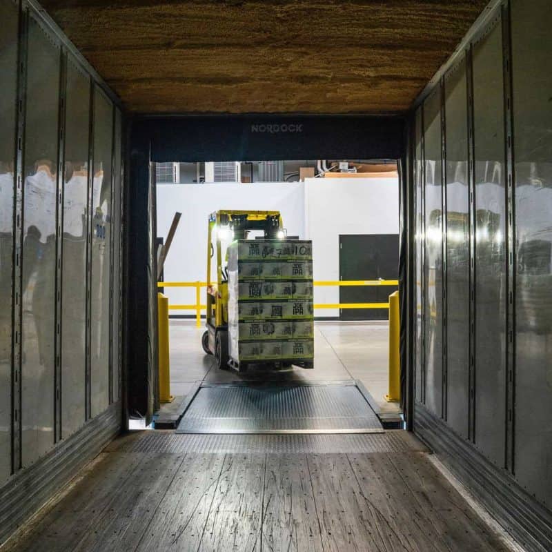 Shrink wrapped pallet being carried off a lorry by a forklift